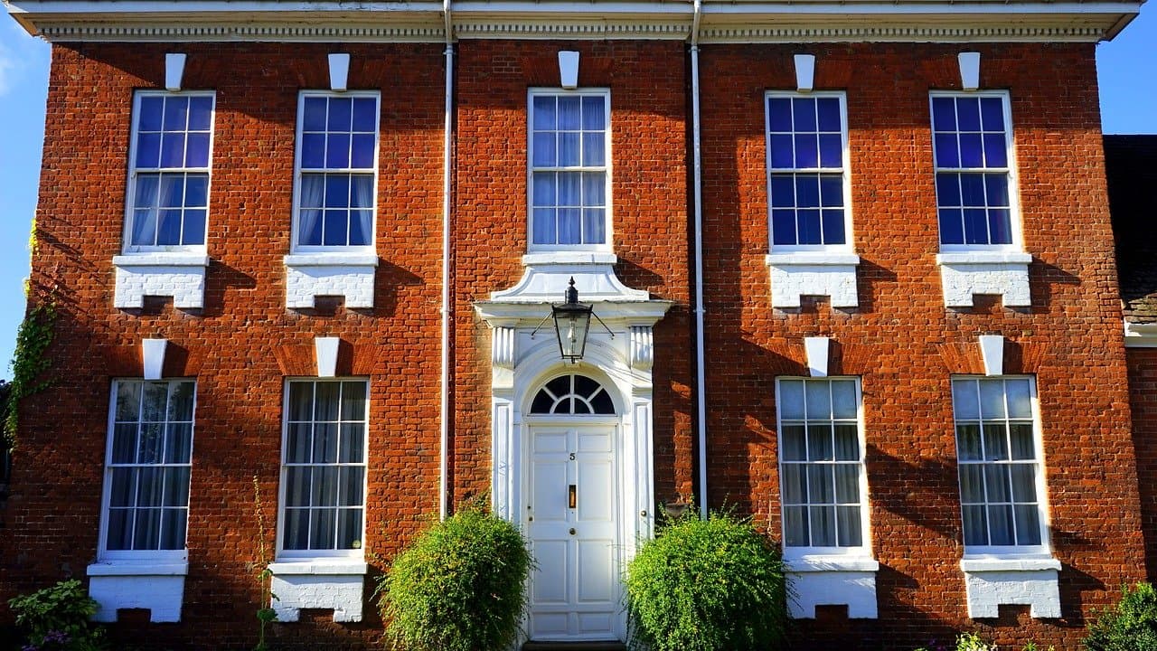 Red-brick British house facade with white-framed windows and a front door