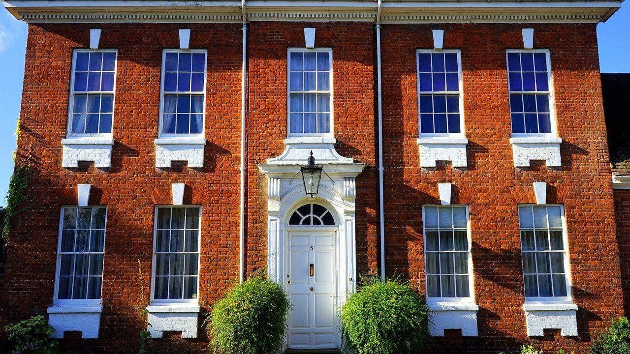 Red-brick British house facade with white-framed windows and a front door