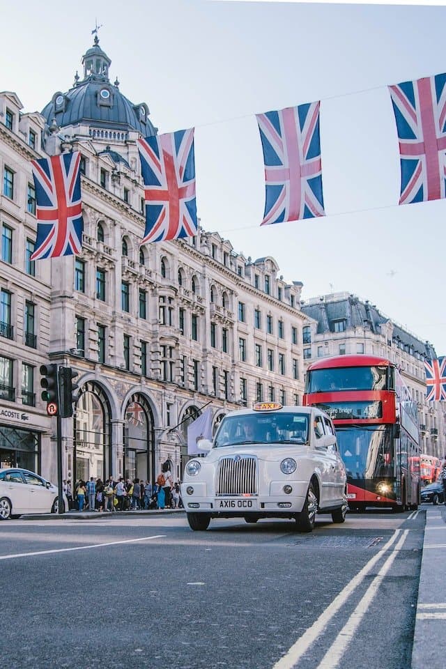 London street scene with Union Jack flags, a black cab, and a red double-decker bus